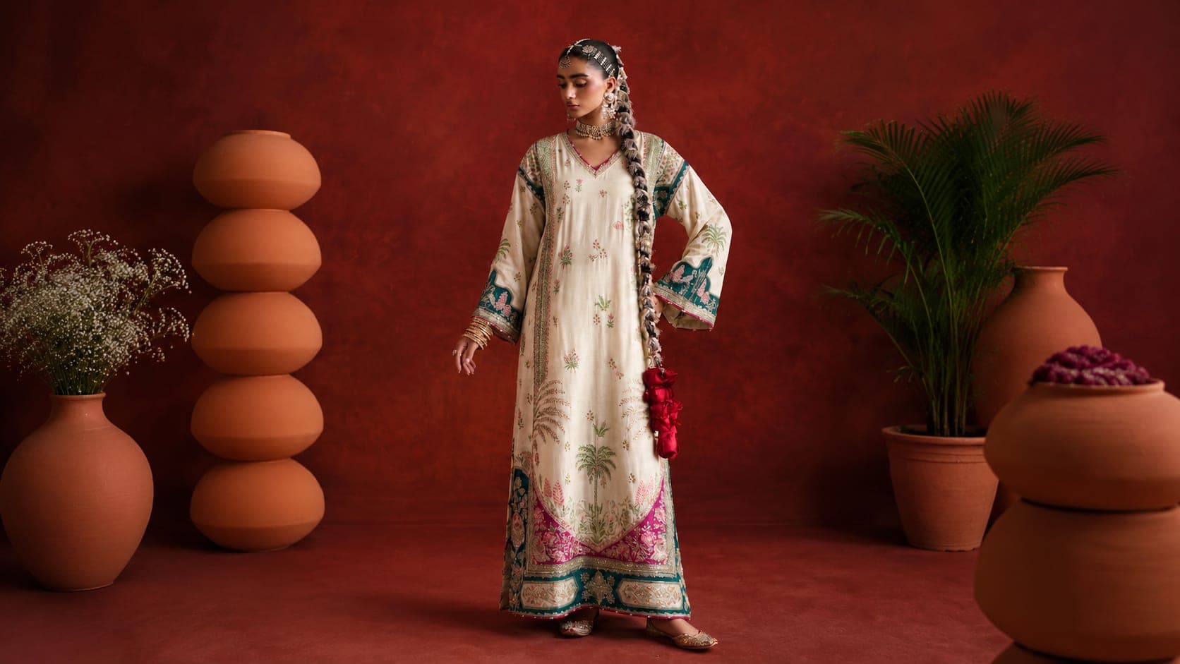 Ivory silk kaftan with palm-motif print and teal embroidered borders against a terracotta studio backdrop