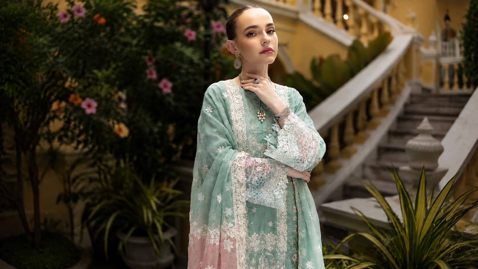 Mint embroidered chiffon suit with a scalloped lace dupatta, in a courtyard garden by a white staircase